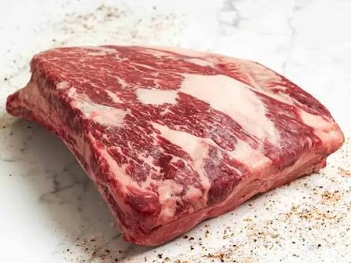 Raw slab of beef plate ribs with heavy marbling on a marble counter