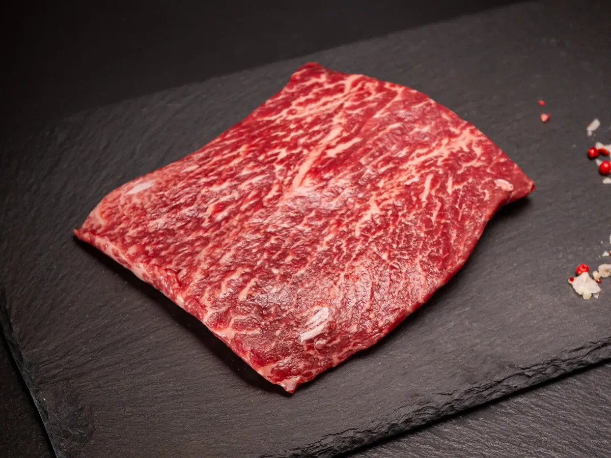 Raw marbled flat iron steak on a dark slate board